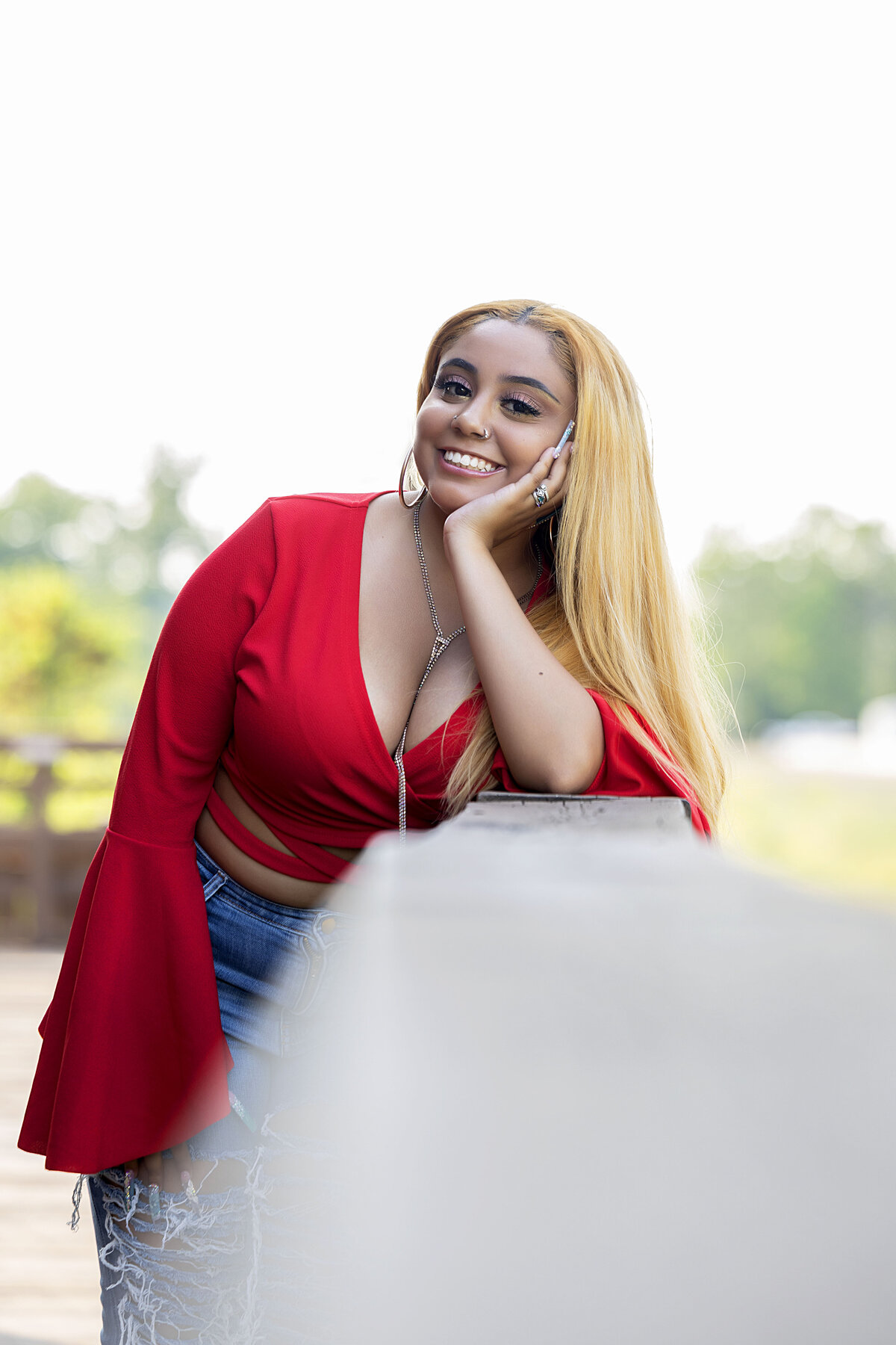 Senior girl with red shirt and blue jeans leaning on banister