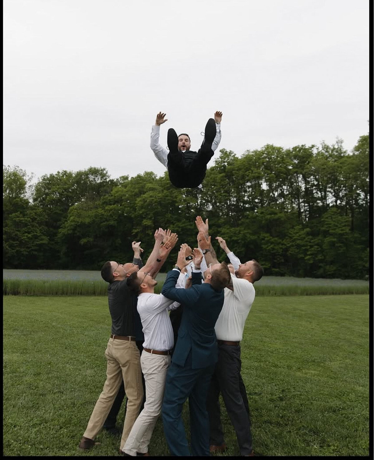 Groomsmen tossing the groom in the air