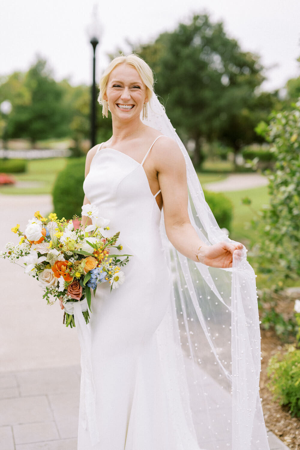 bride-with-orange-bouquet-holding-pearl-veil