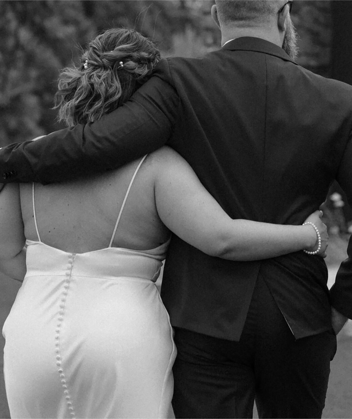 close up of bride and groom as the bride has her arm around the groom who wears a nice suit