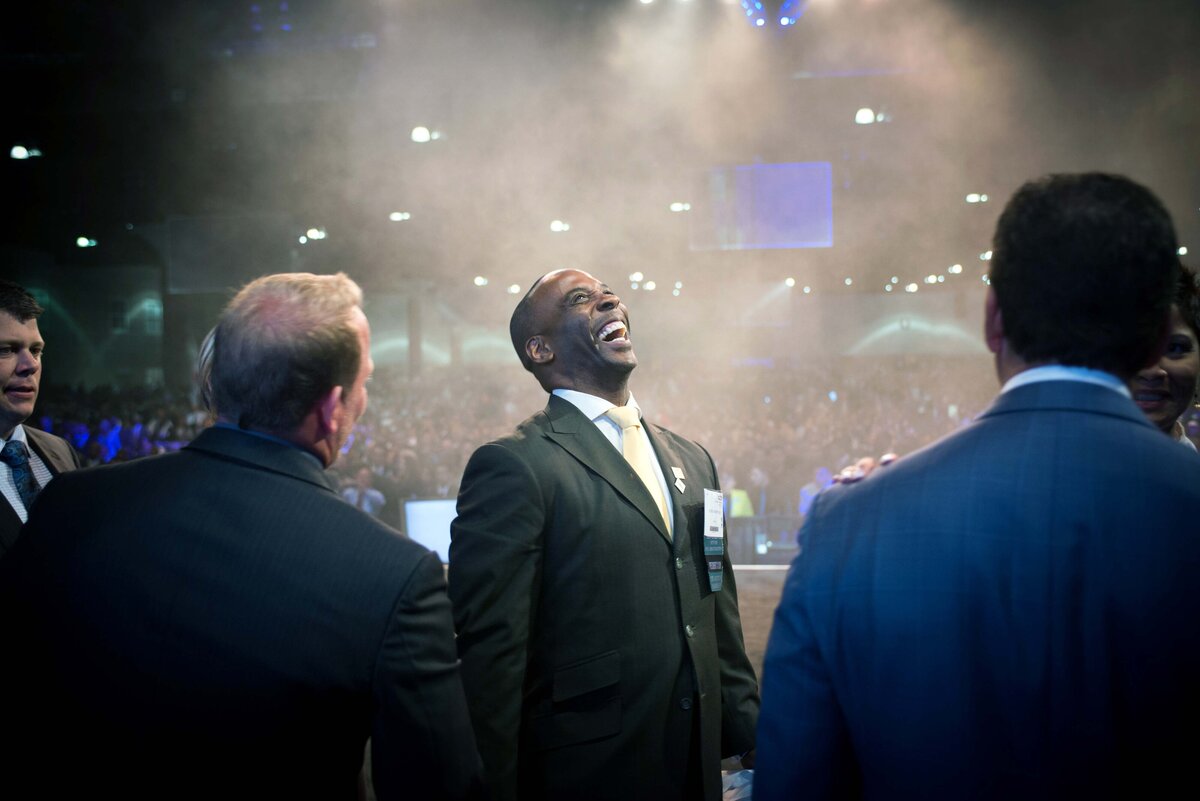 Man laughs after shaking hands onstage to receive a network marketing promotion
