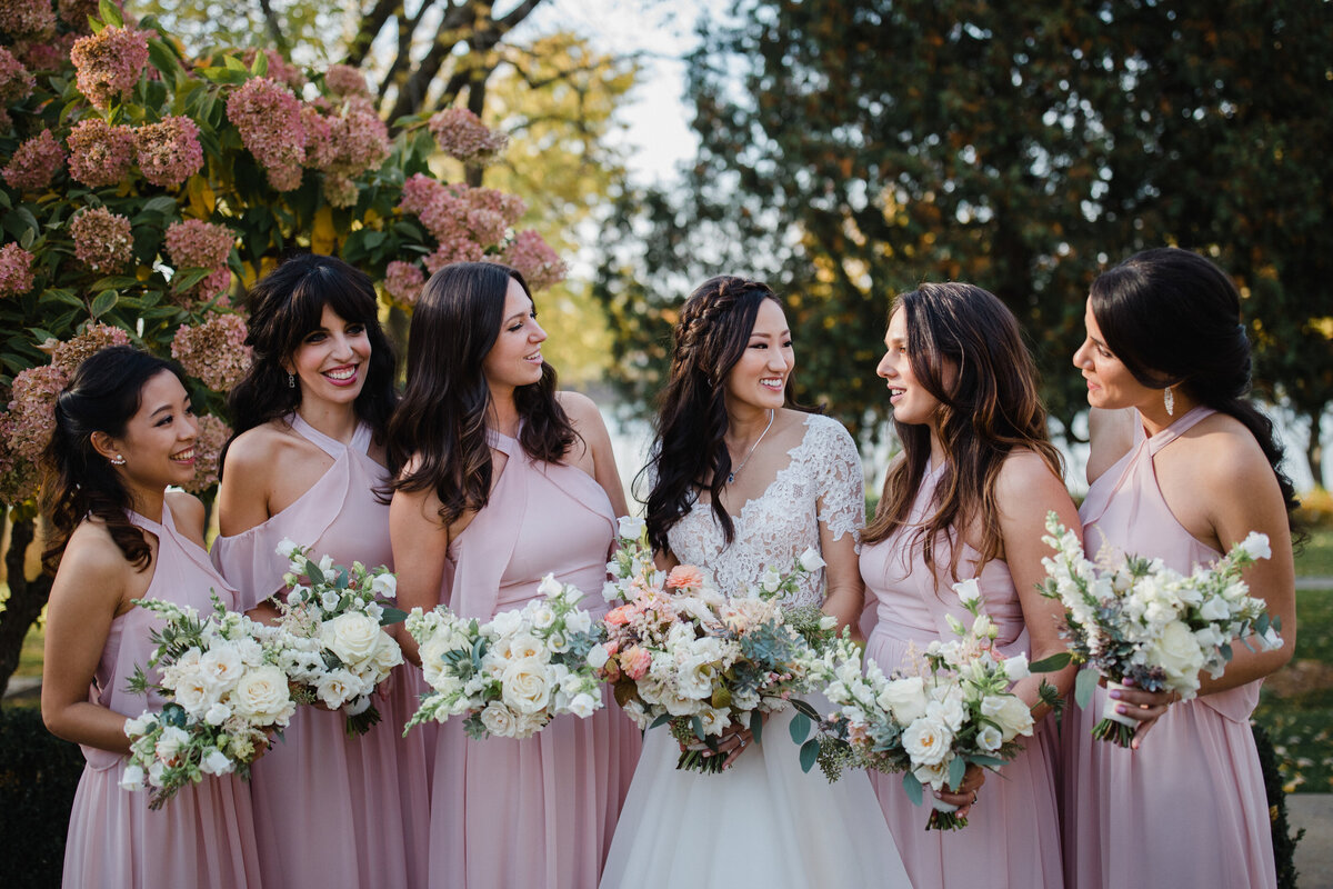 A bride and bridesmaids pose with bouquets in a park in Montreal.