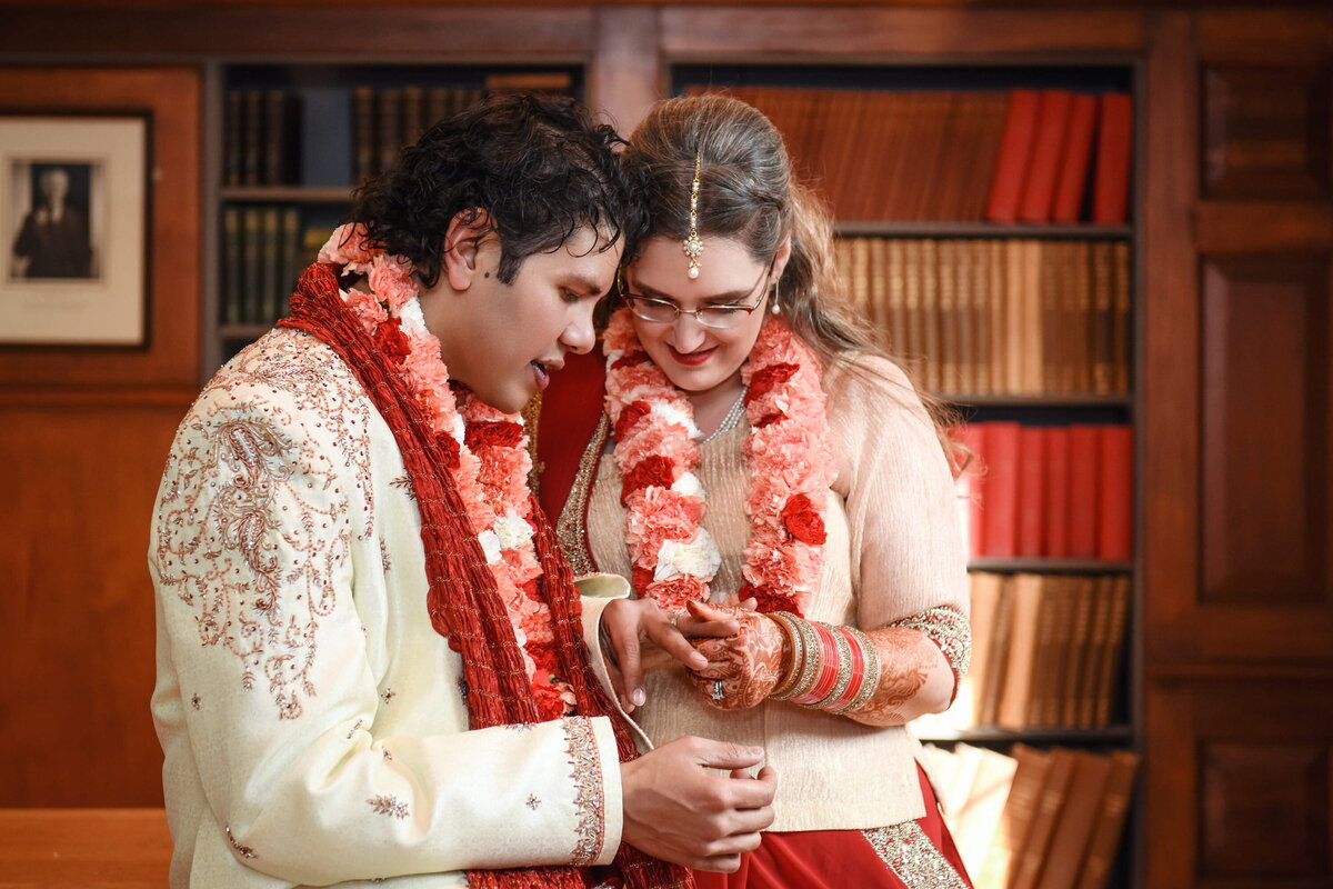 Bride and groom exchanging glance, floral garlands, library.