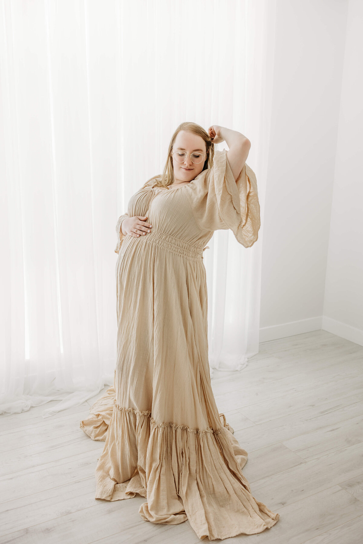 Pregnant woman in Luci Levon Photography studio maternity portraits in beige dress