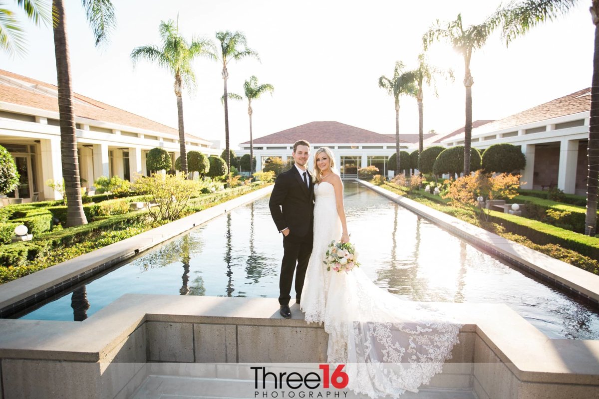 Bride and Groom pose while standing on the wall surround the Richard Nixon Library reflection pool