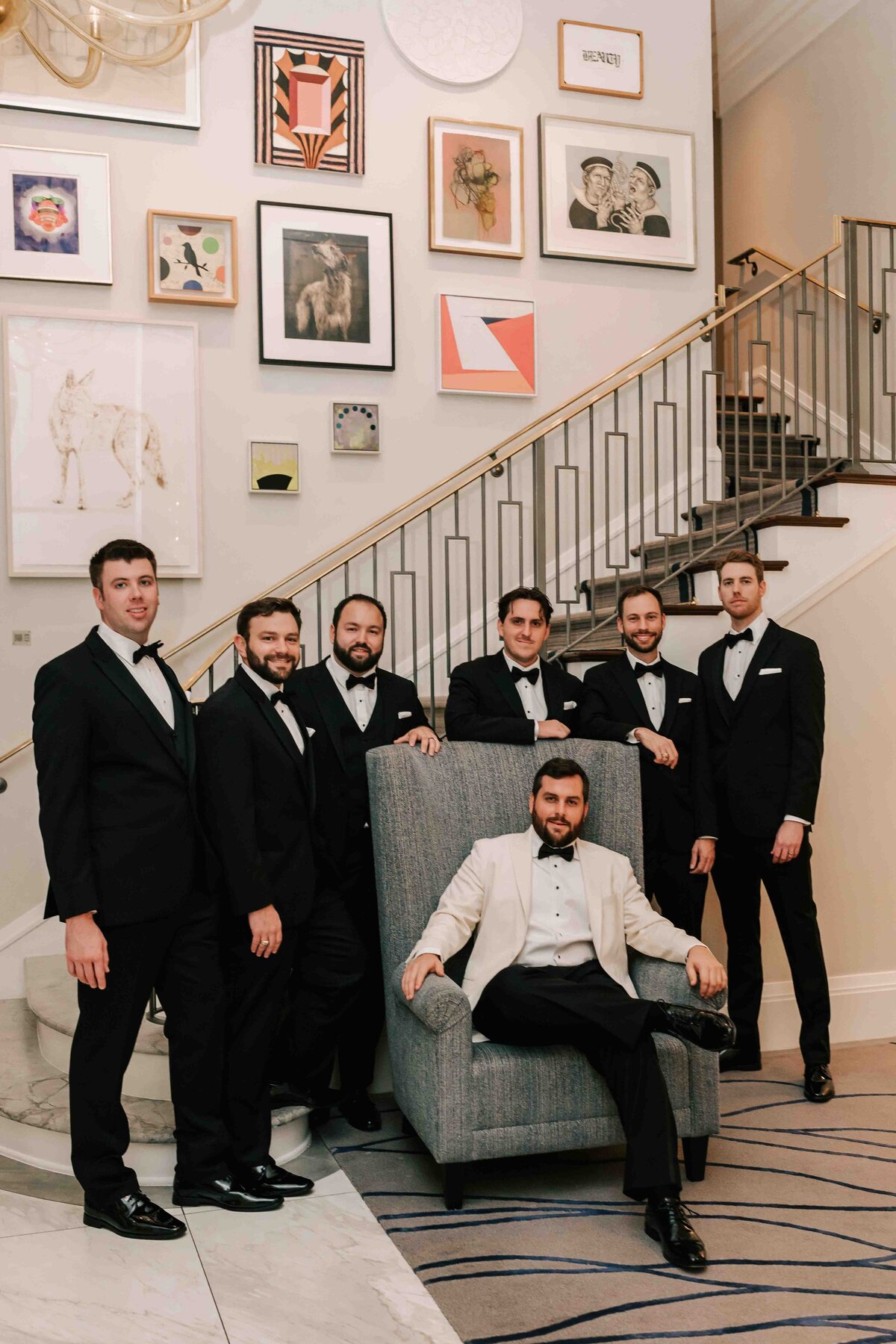 grooms party stands in Lancaster Hotel lobby, while groom sits in chair.