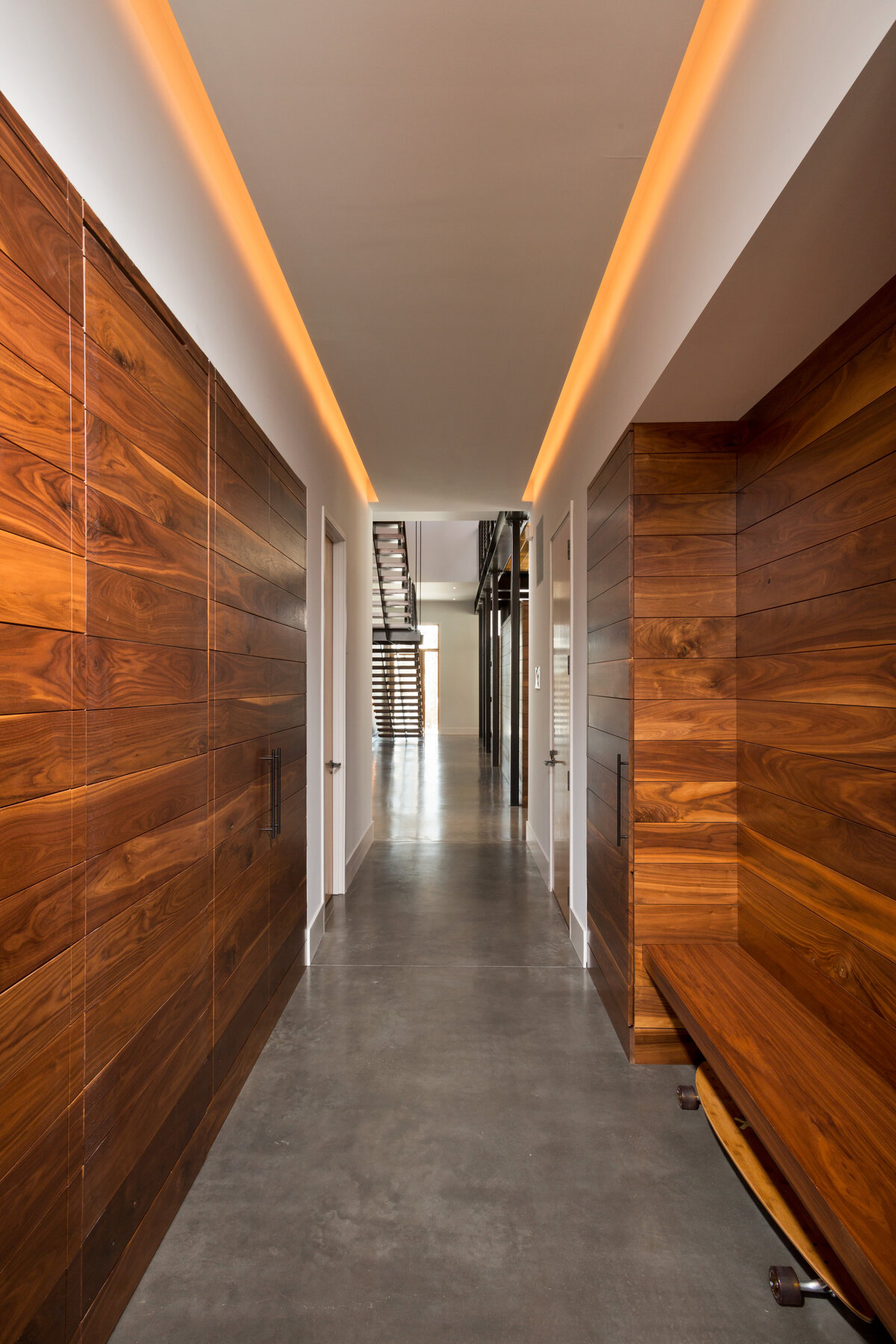 Hallway with dark wood walls and concrete floor