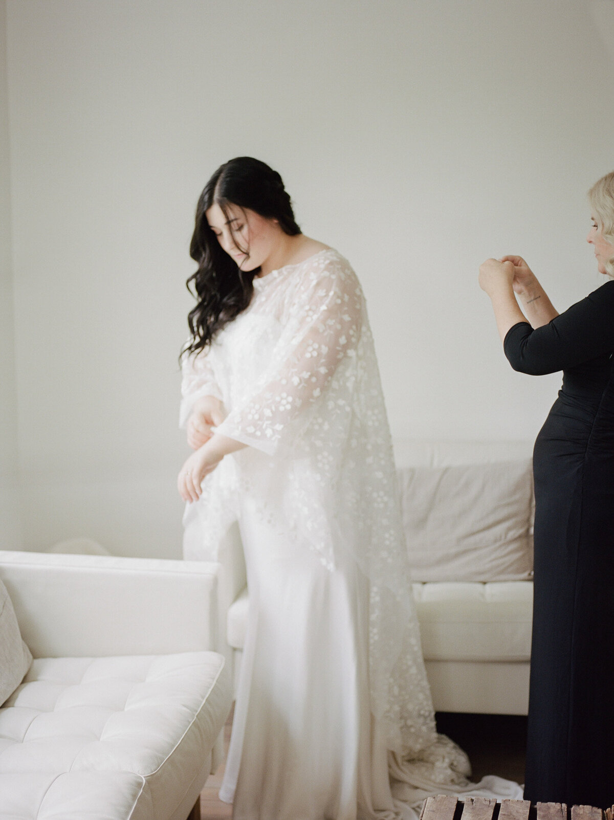 bride in bridal cape prepares in white getting ready space, Michigan wedding venue