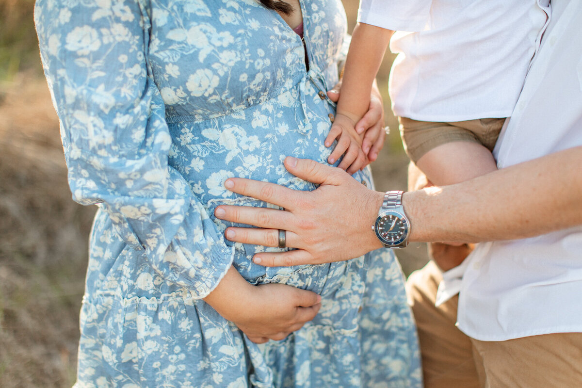 Maternity photo of a pregnant woman in a field with her family, captured by San Antonio family photographer Sara James.