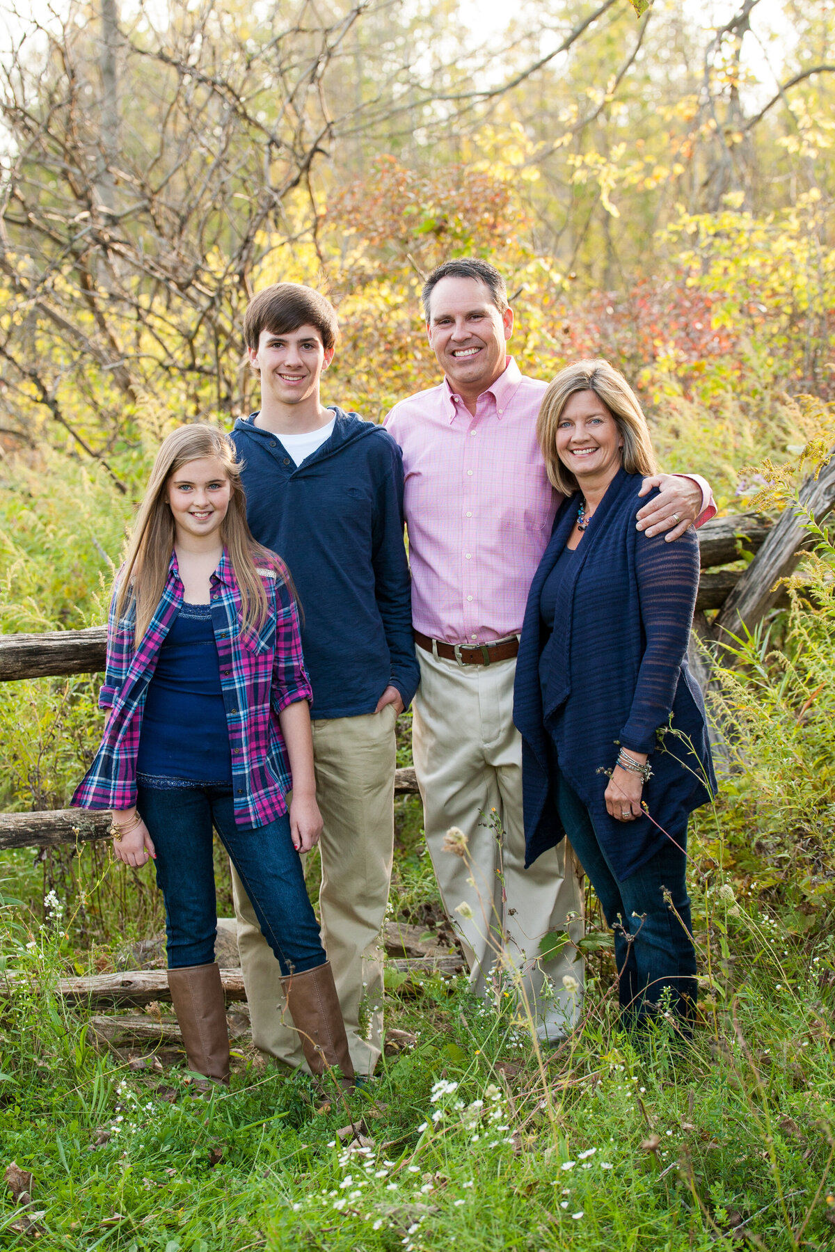 Family portrait taken of a high school senior guy from Victor, NY with his family by a fence