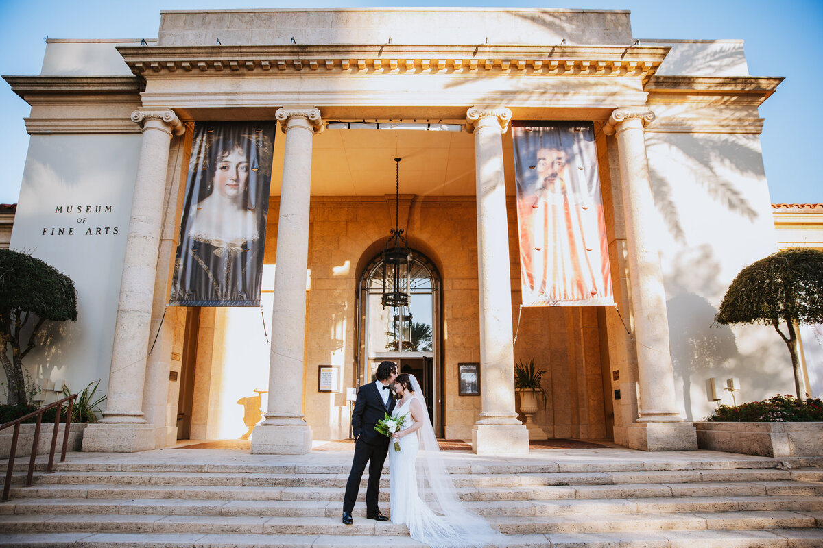 bride and groom kissing on the steps of the museum of fine arts in st pete florida