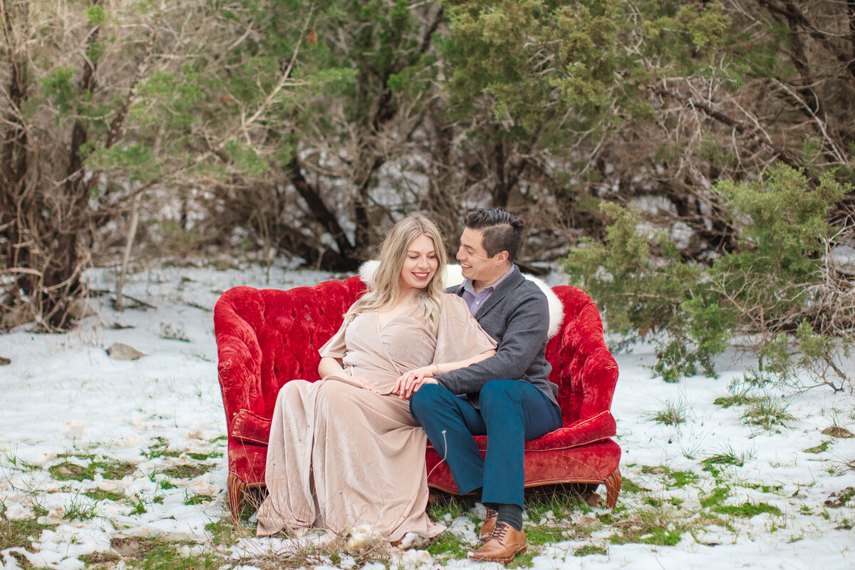 velvet dress  red velvet couch in snow engagement session by New Braunfels wedding photographer Firefly Photography