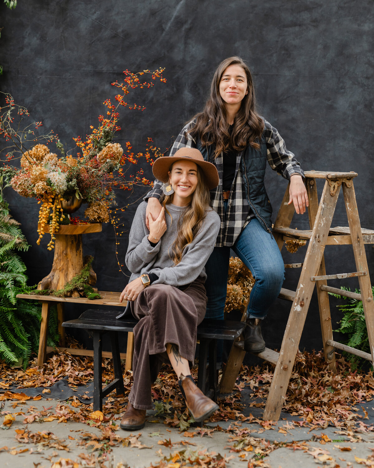Two girls sitting hand in hand leaning against ladder