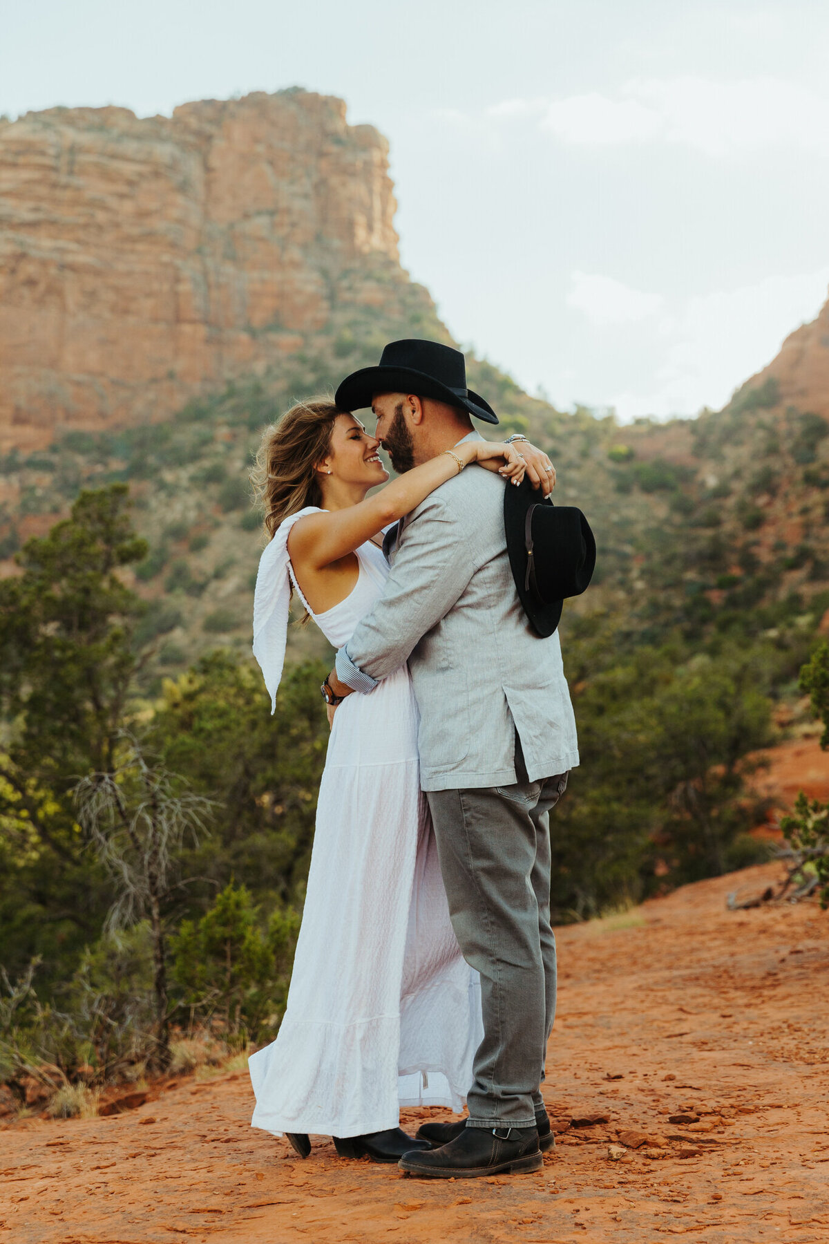 western couple standing for engagement photos with red rock backdrop