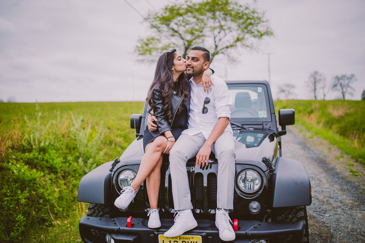 engaged girl kissing boy on top of the hood of jeep wrangler during their engagement session
