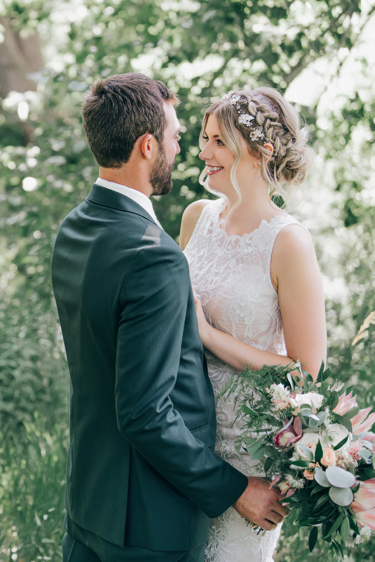 A bride and groom kissing in a forest on their Summer wedding day