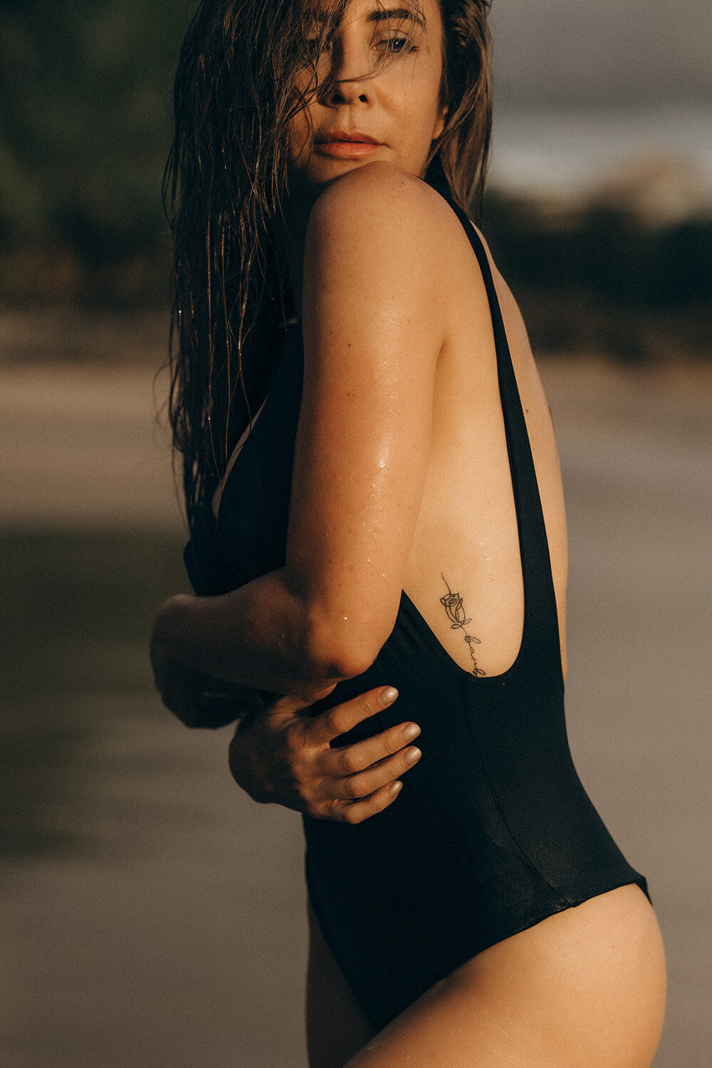 brand photograph for a swimsuit model on sunshine coast beach with a girl standing side on revealing a tattoo
