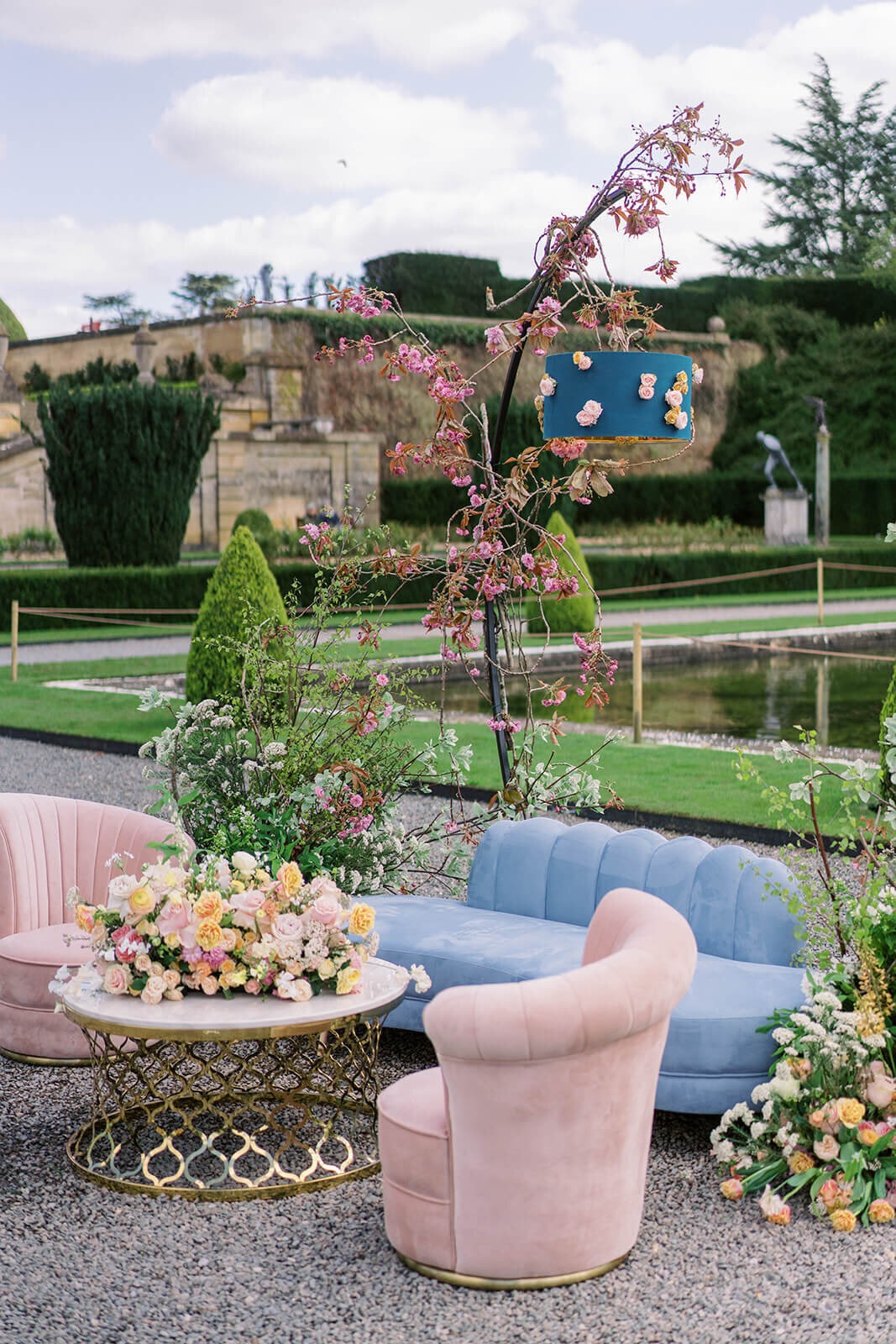 wedding drinks reception lounge set up in the gardens of blenheim palace with pink and blue lounge seating and pink and peach flowers