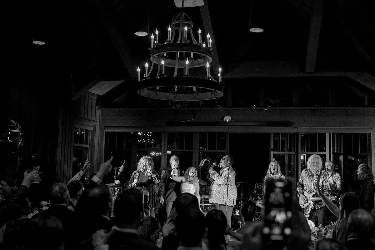 Bride and groom celebrating on stage with a live wedding band during an upscale reception in Highlands, North Carolina.