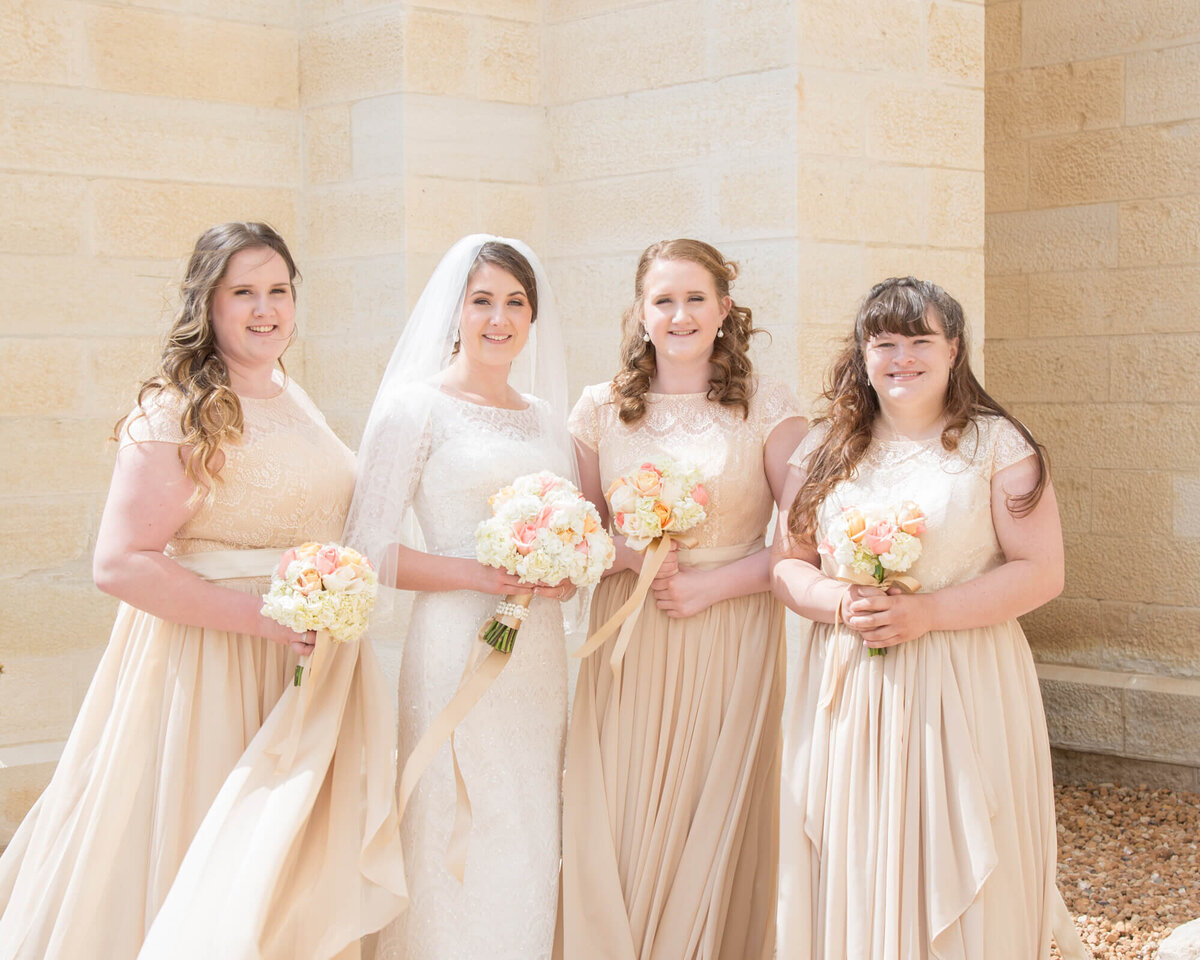 bride and bridesmaids in cream dresses holding white, cream, and pink bouquets