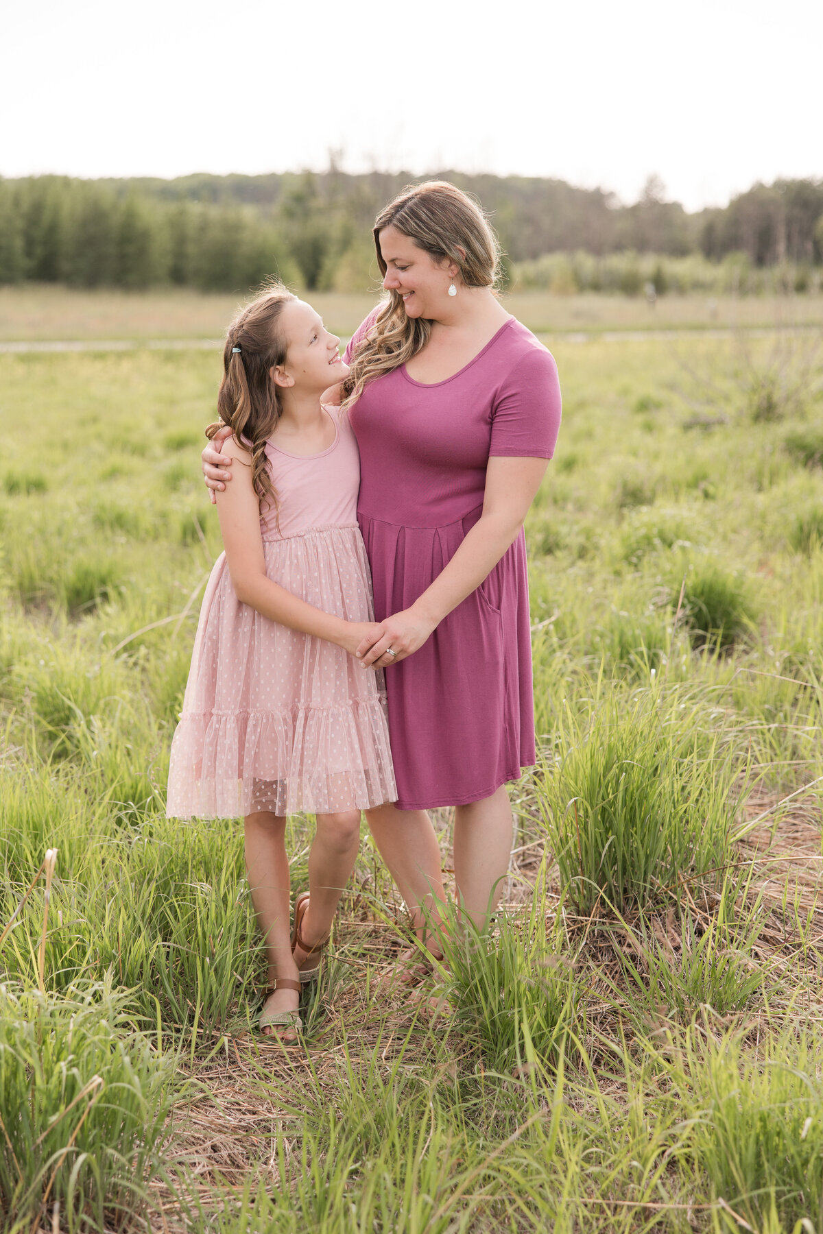A mother and daughter look at each other lovingly in a grassy field