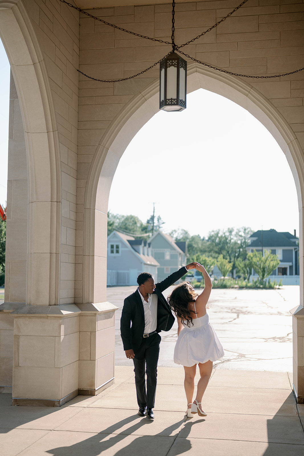 Fun Kalamazoo engagement session moment with bride-to-be twirling in a white dress.