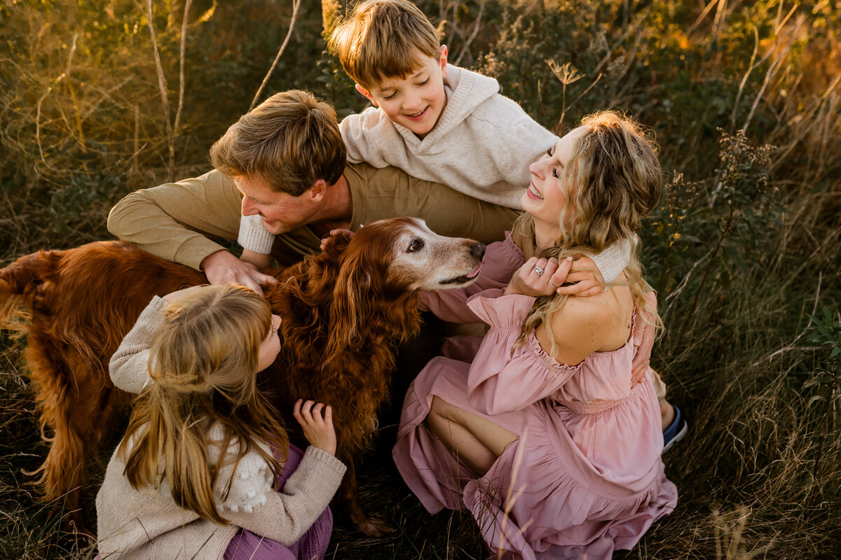 family snuggling with their golden retriever