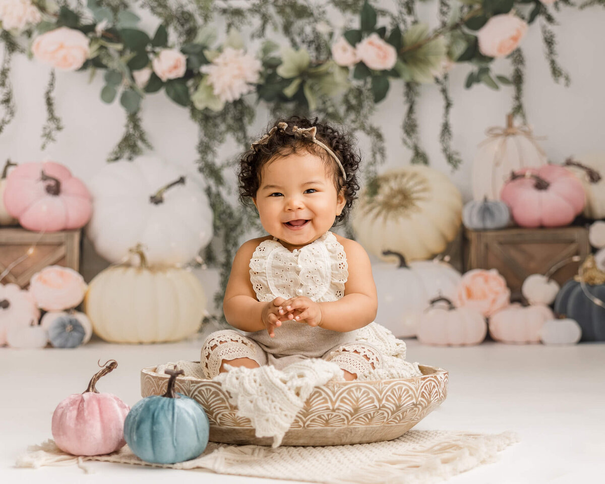 super happy baby girl smiling with pumpkins in background  for milestone baby photography session in portland oregon by Ann Marsall