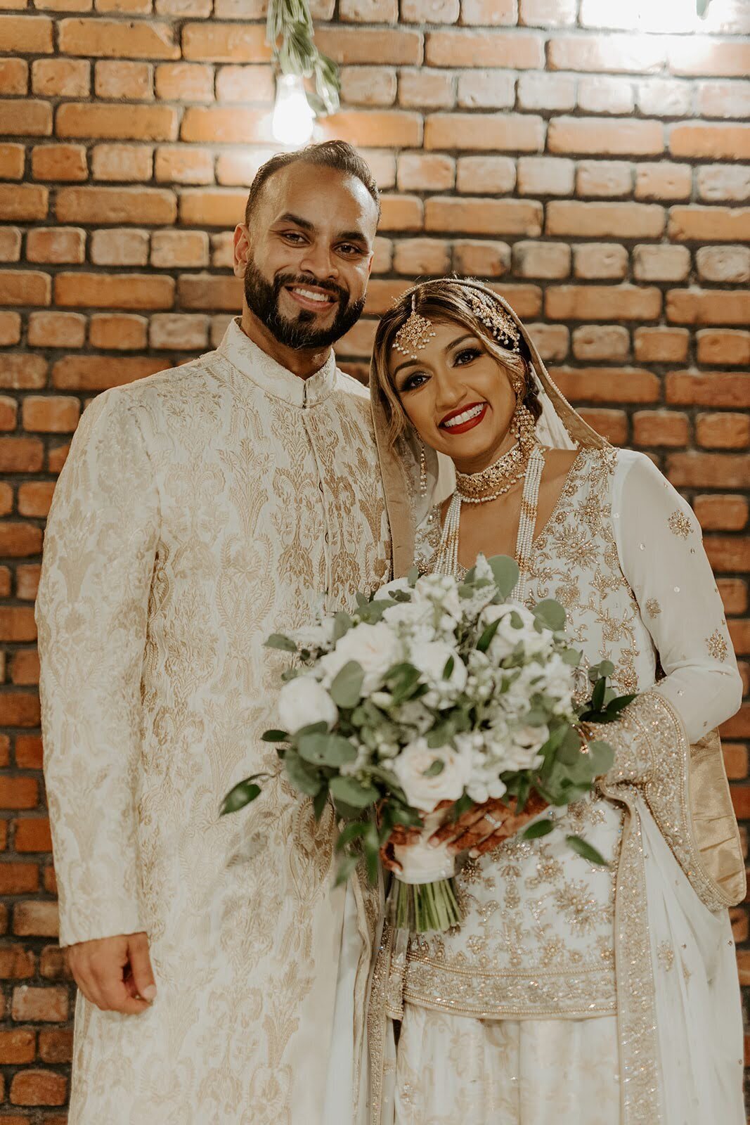 Bride and groom smile after their wedding ceremony with a white and greenery bouquet at the Bowery House and Gardens.