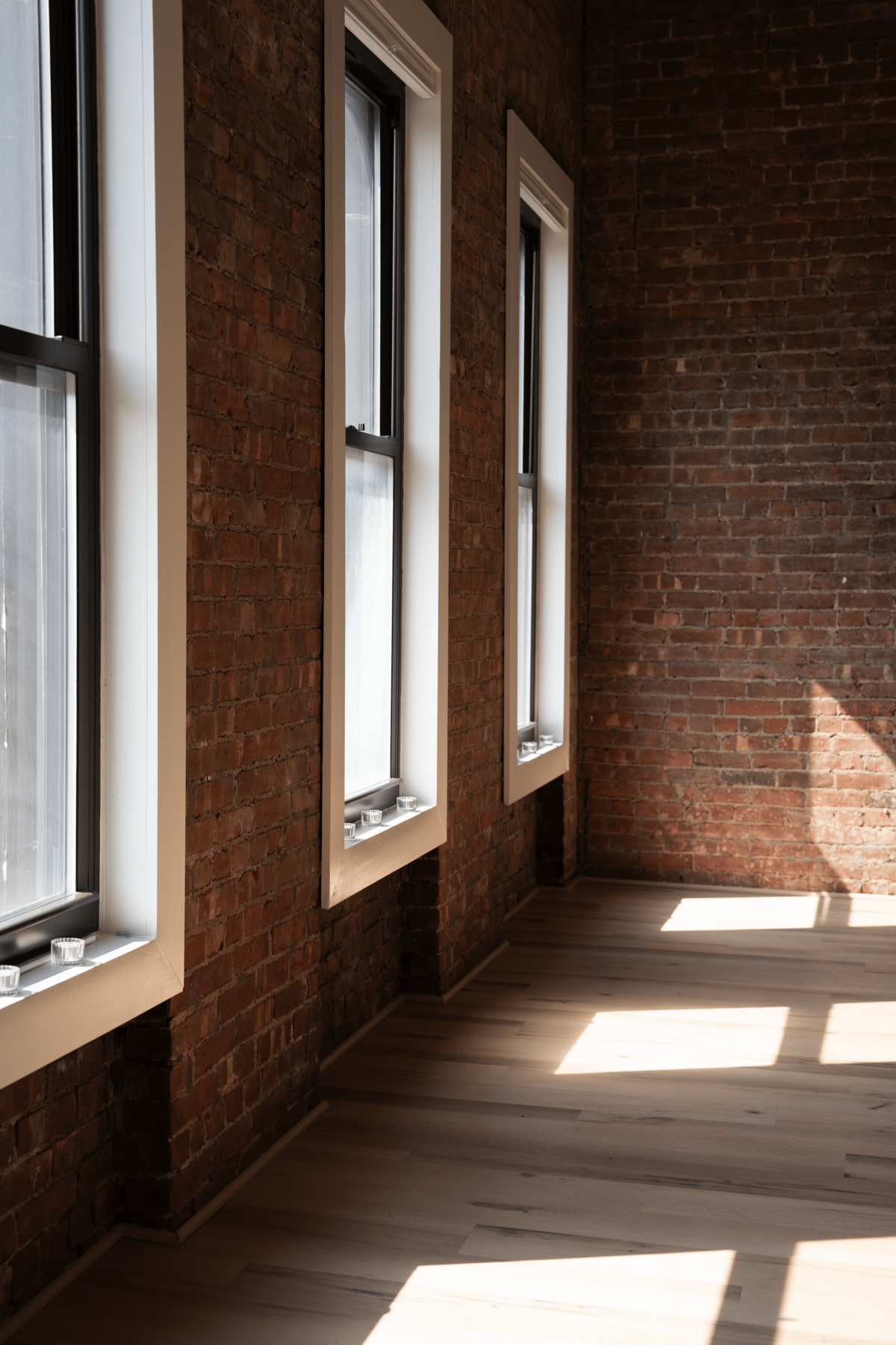 Rental studio space in Greenpoint with brick walls. Natural light pours in through large rectangular windows.