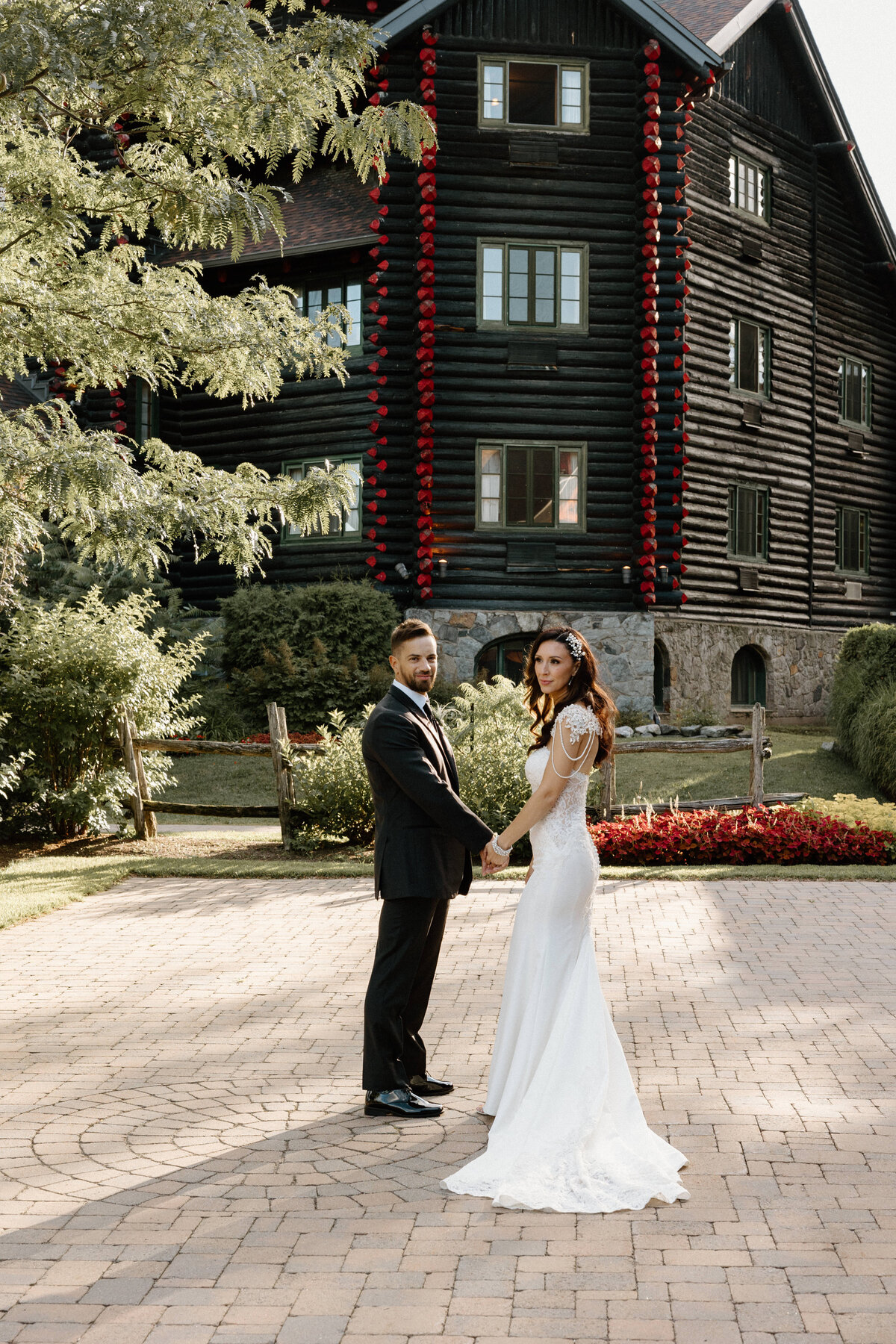 A bride and groom holds hands while posing in front of their wedding venue