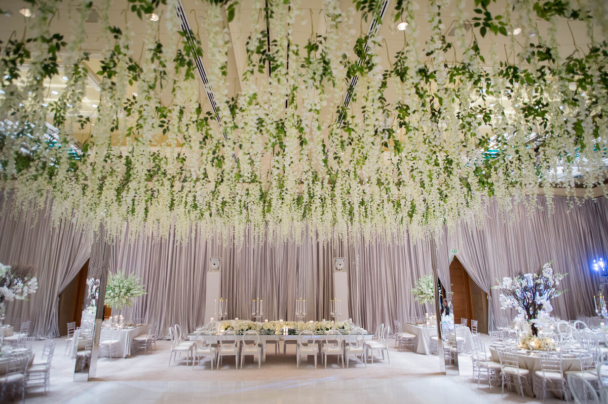 Elegant wedding reception decor with white floral ceiling, captured by Rodrigo Varela Photography.