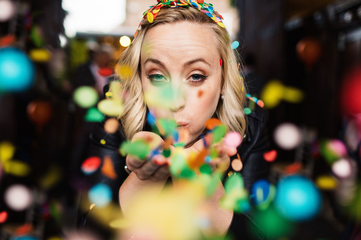 informal picture of a bride blowing colourful confetti