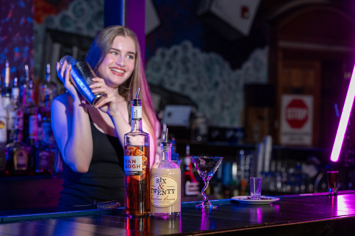 A bartender mixing a drink in a shaker 