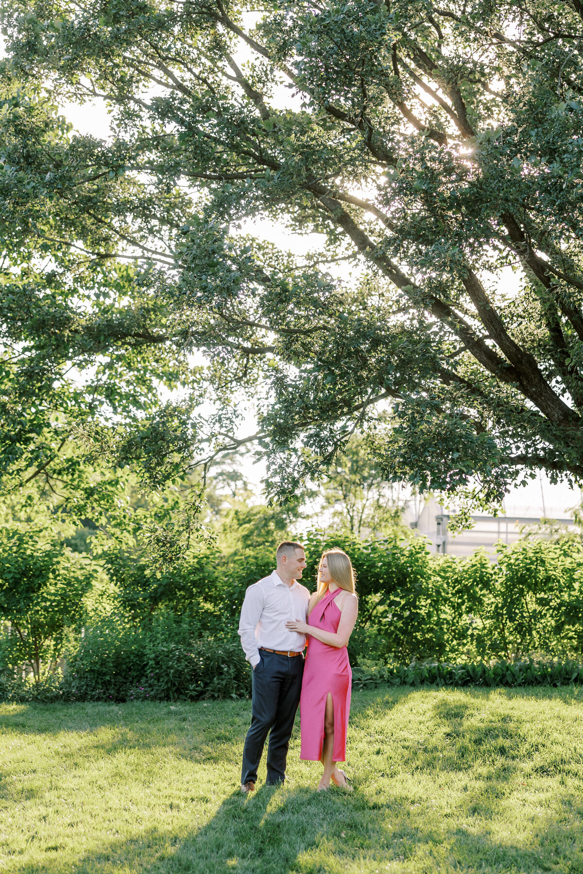 Engaged couple smiling at each other surrounded by lush Columbus garden shot by Philadelphia photographer.