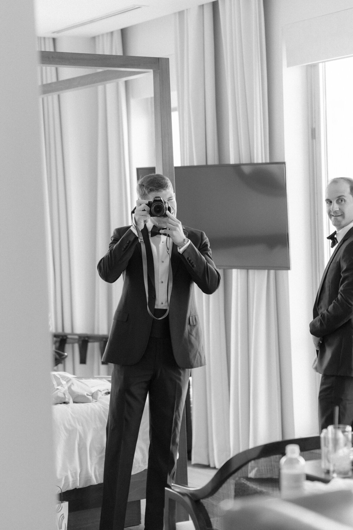 Groom getting ready at the Dewberry Hotel. Fall wedding in Charleston. Groom holding camera back at photographer for fun photo.