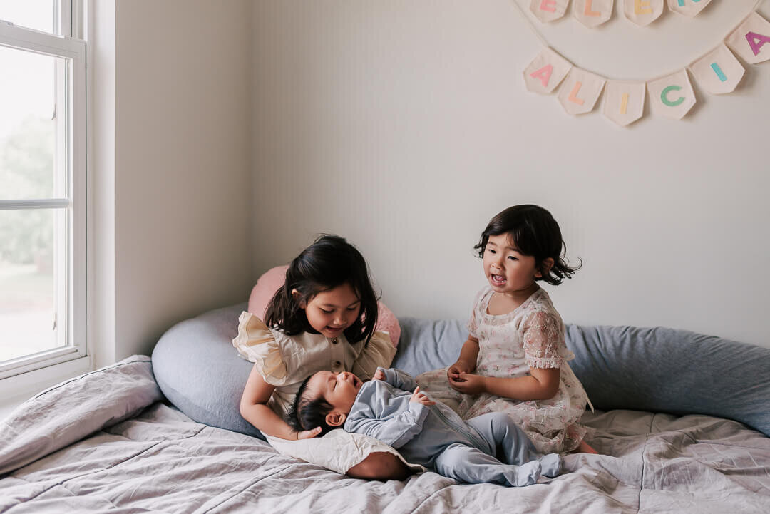 Two big sisters singing a song to their new baby brother, taken by Northern VA newborn photographer