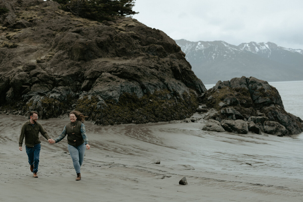 Couple running while holding hands on the beach.