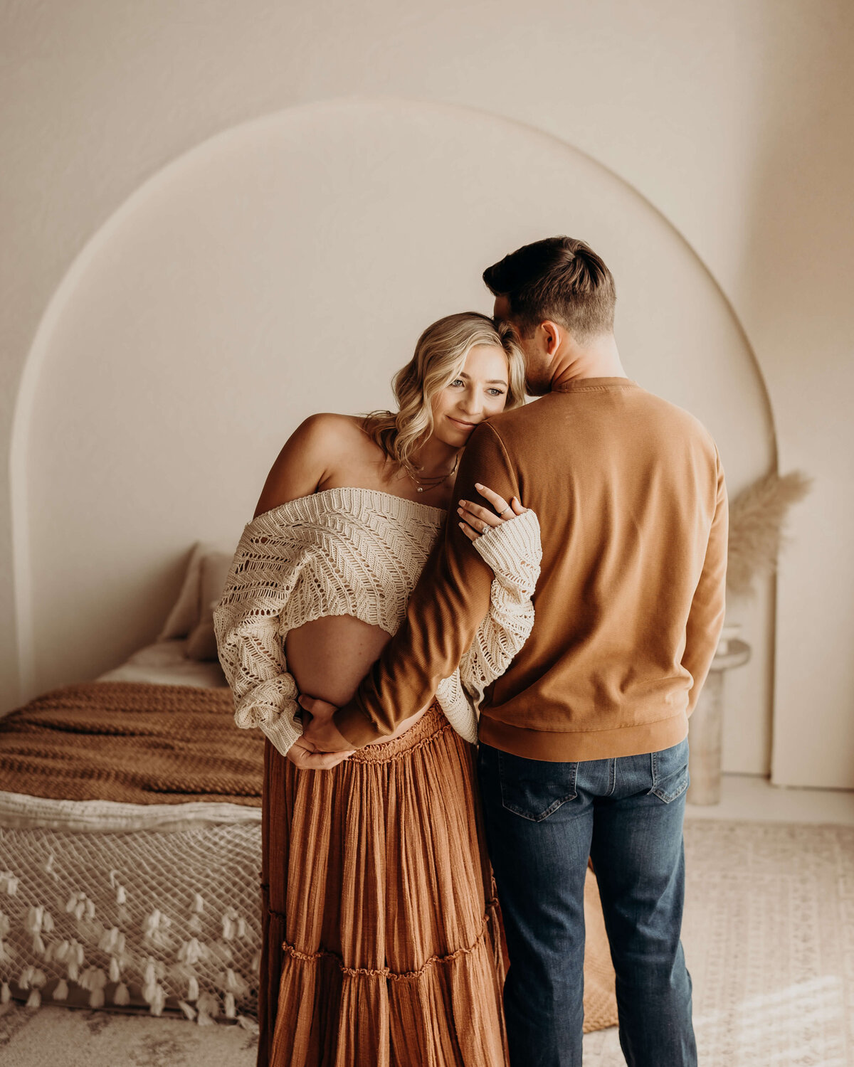 pregnant woman hugs her husbands arm while smiling