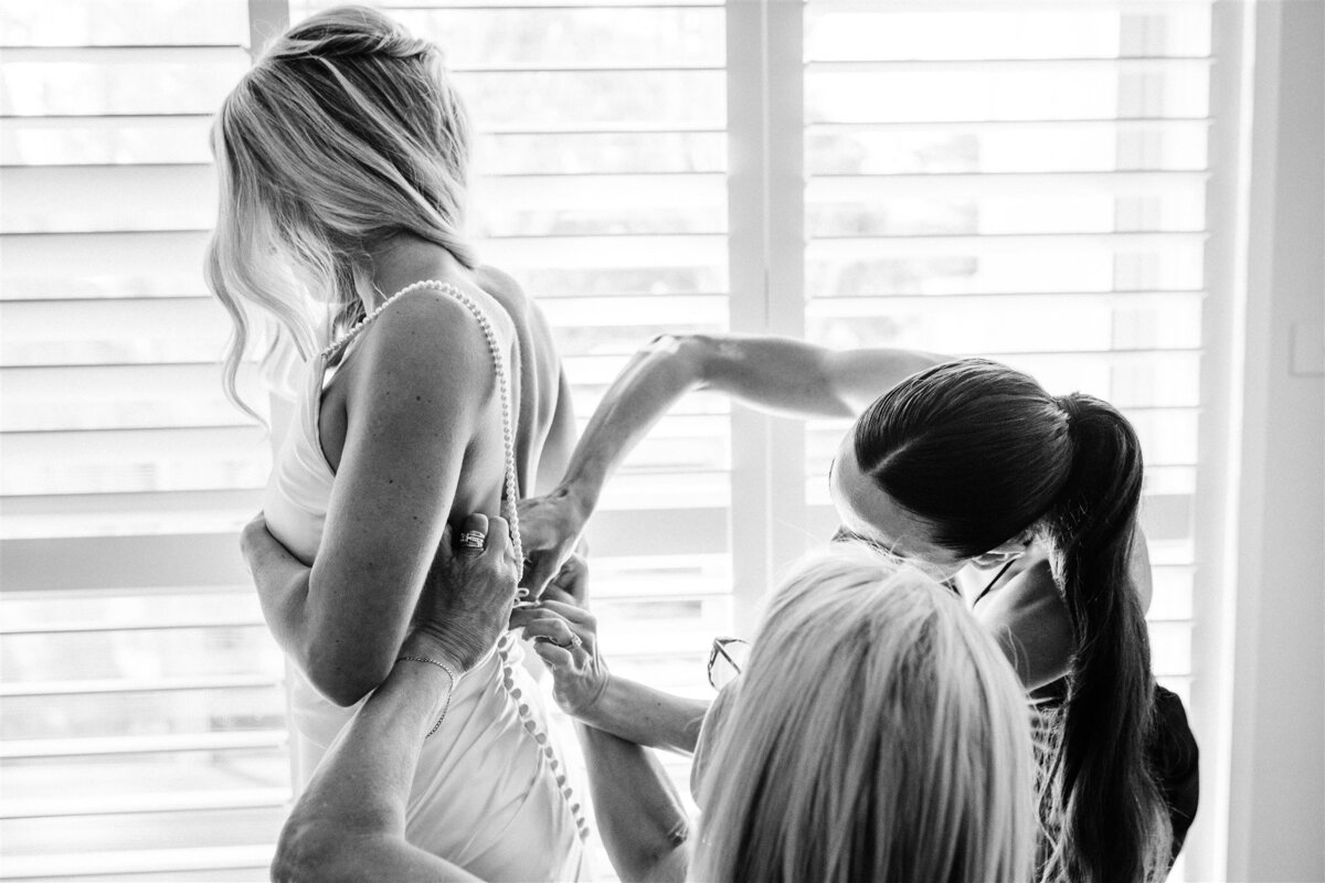 Michaela's bridesmaids helping her out with her beautiful wedding dress before the wedding ceremony