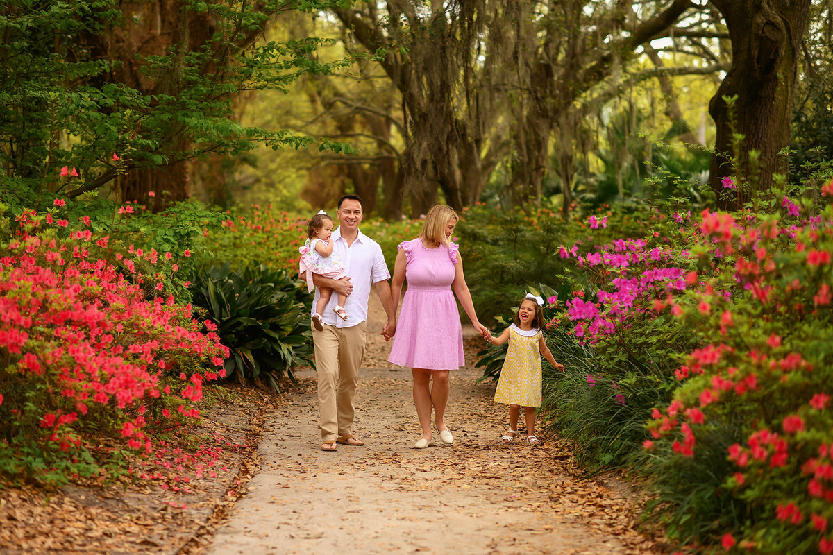 Family walks together among azalea blooms in Hampton Park during their Family Photos in Charleston, SC.