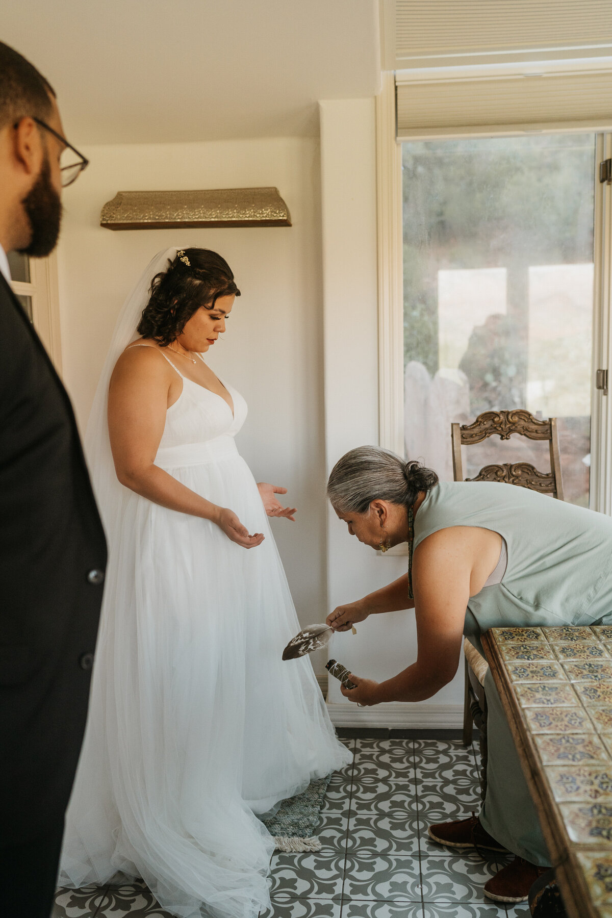 A person cleansing someone in a wedding dress with burning sage 