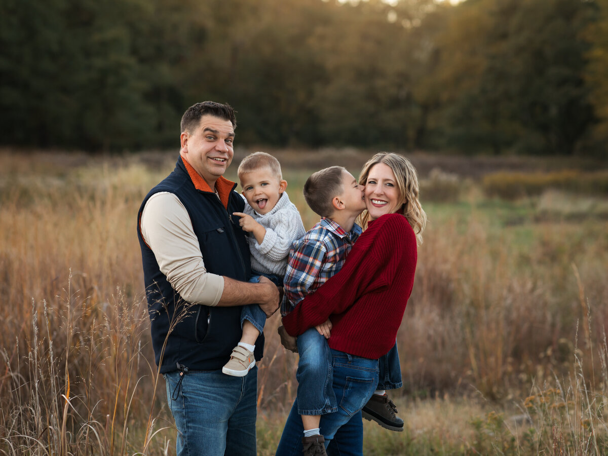 mom dad and two sons posed in field for family photoshoot cleveland family photography
