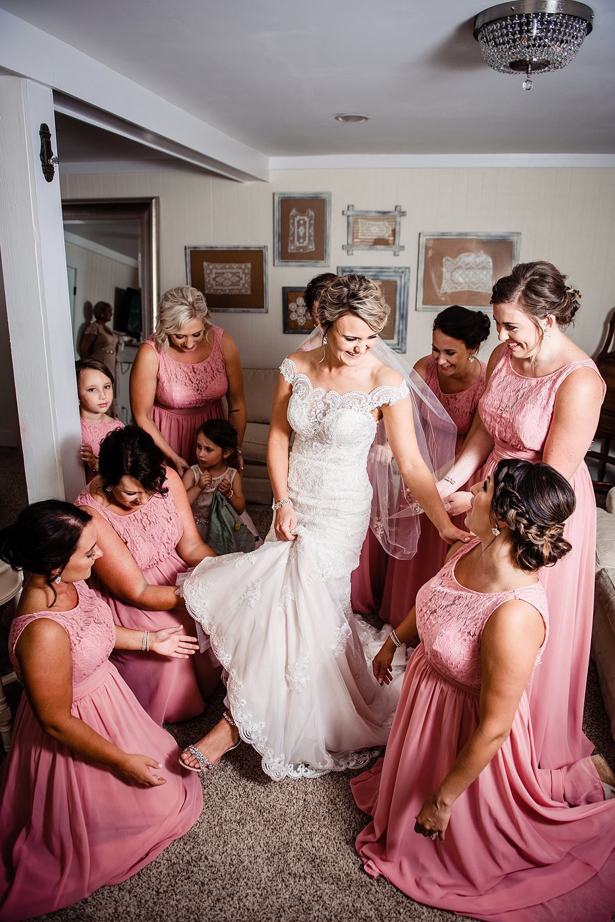 Bridesmaids gathered around and helping bride getting her shoes on