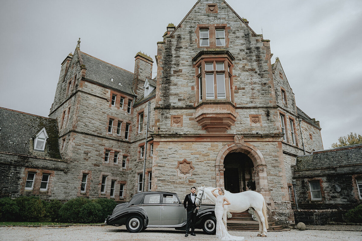 Bride and groom posing with horse and car in front of Ireland castle