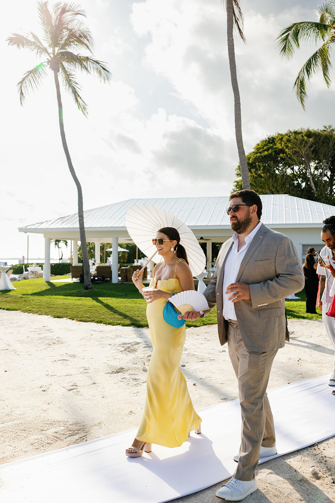 A bridesmaid in a yellow gown walks down the aisle with a groomsman during Andressa and Jonathan’s oceanfront wedding at Table Key, Islamorada. Captured by Claudia Amalia, destination wedding photographer.