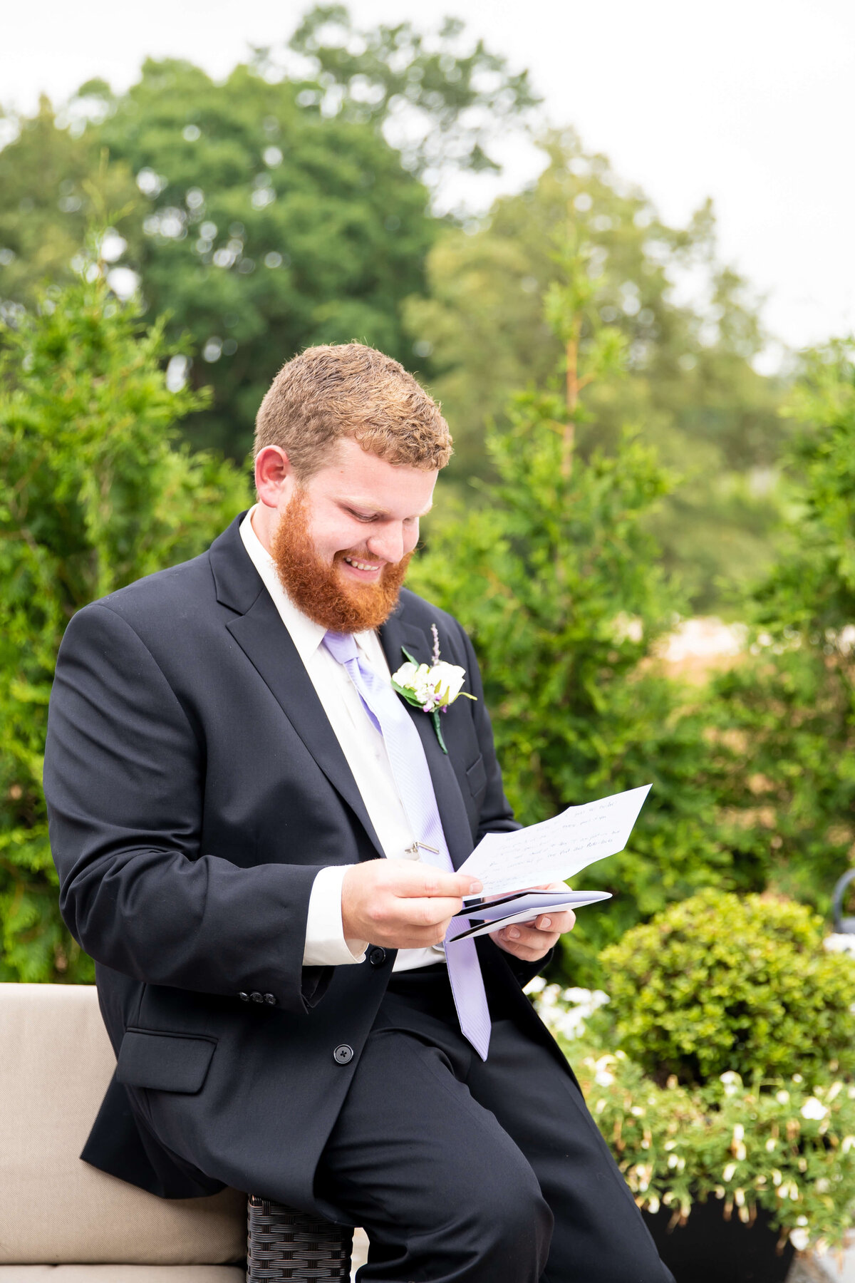 Groom smiling whilst reading letter