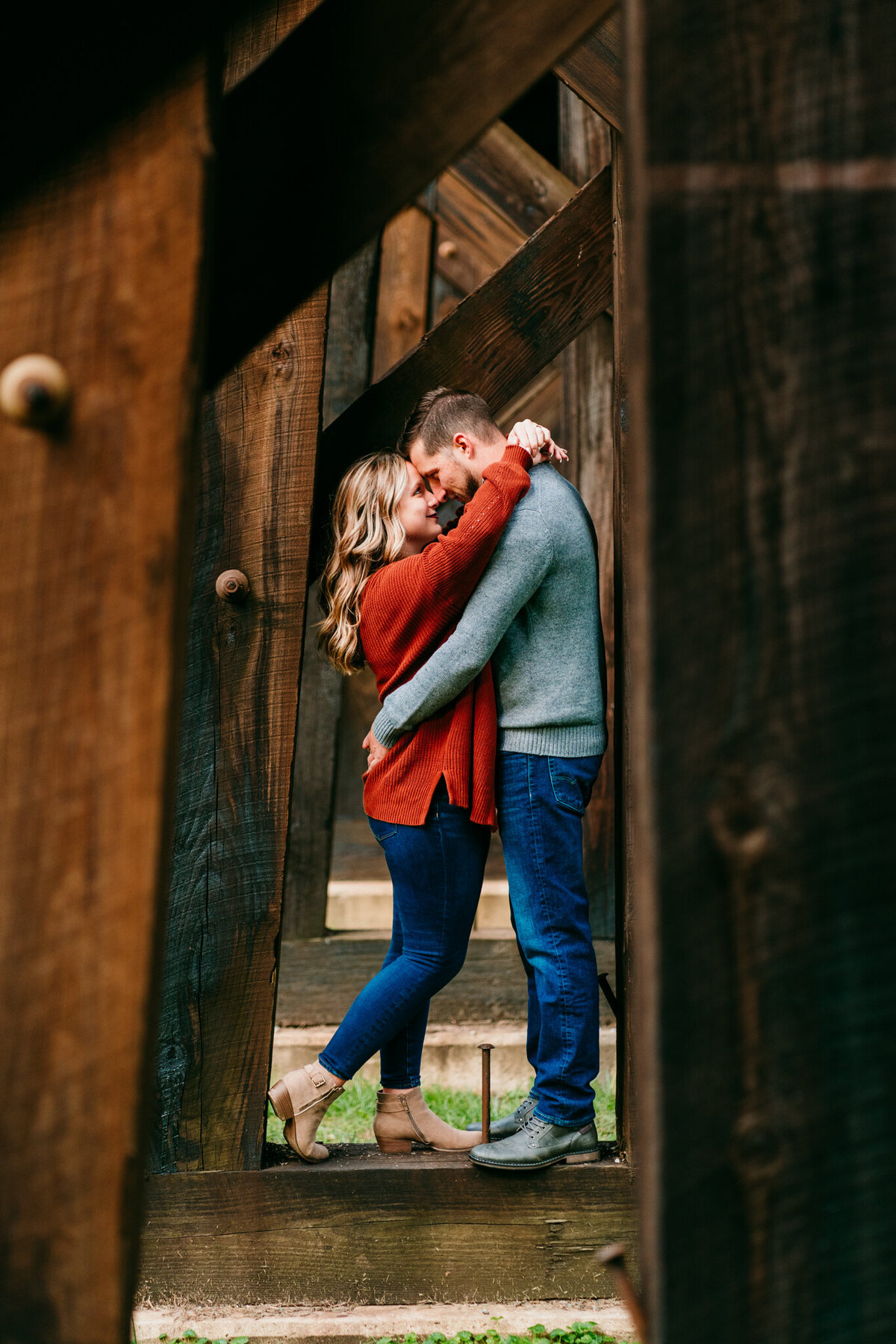 Couple kissing under covered wooden bridge beams