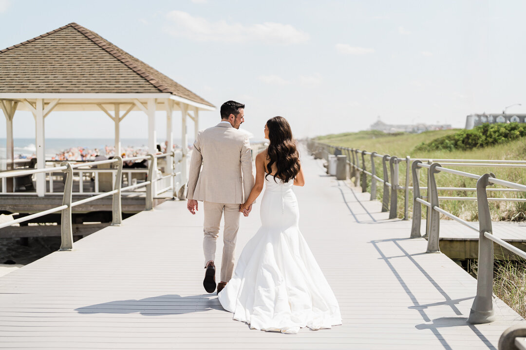 Bride and groom walking on boardwalk at romantic beach wedding in New Jersey