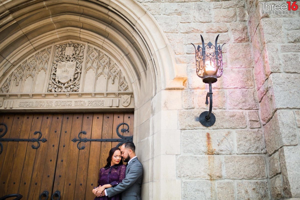 Romantic embrace for engaged couple at the entry doors of an old church